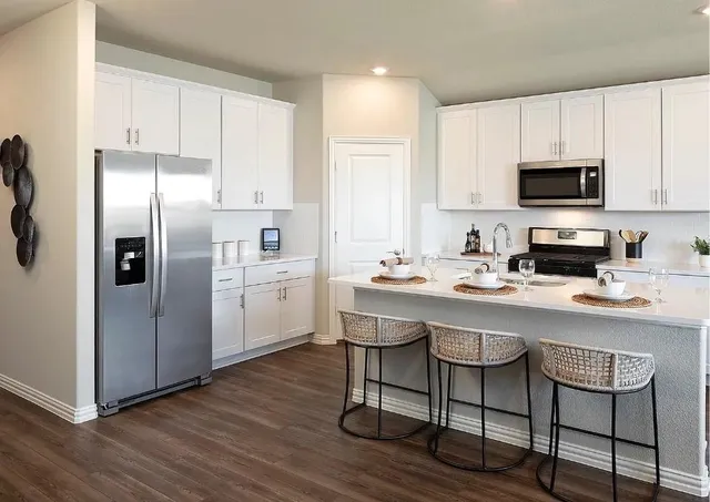 a kitchen with a refrigerator sink and cabinets