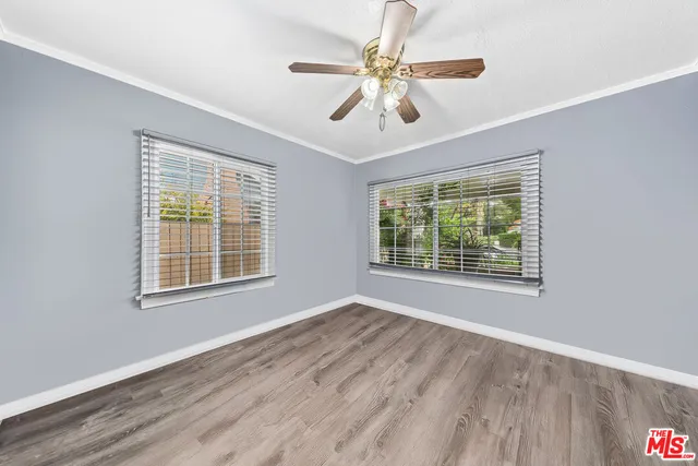a view of an empty room with a window and wooden floor