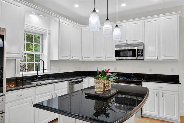 a kitchen with stainless steel appliances kitchen island granite countertop a sink a stove and a microwave