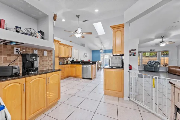 a kitchen with stainless steel appliances granite countertop a stove top oven a sink dishwasher a dining table and chairs with wooden floor