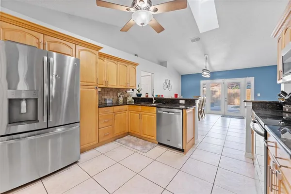 a kitchen with granite countertop a refrigerator a stove a sink and cabinets