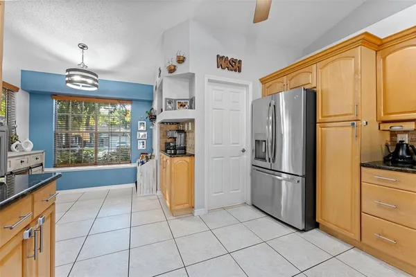a view of a kitchen with granite countertop living room and stainless steel appliances