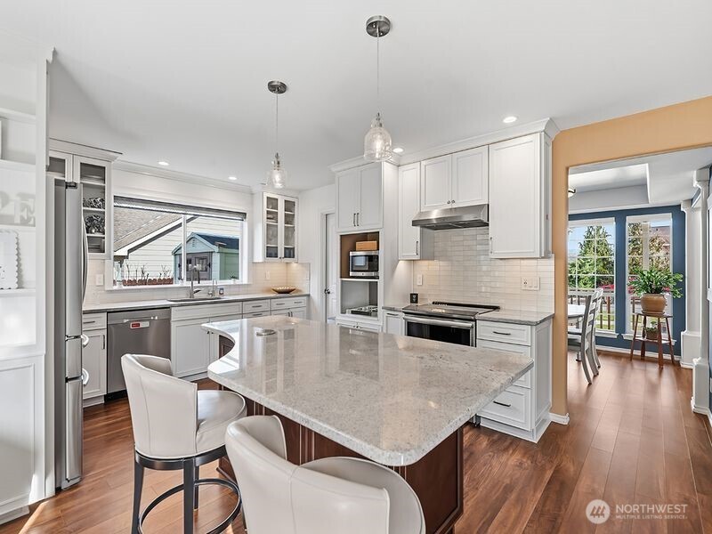1504 Fuller Street Wenatchee, WA 98801 - Photo 12 of 38 a kitchen with stainless steel appliances granite countertop a stove top oven a sink a dining table and chairs with wooden floor