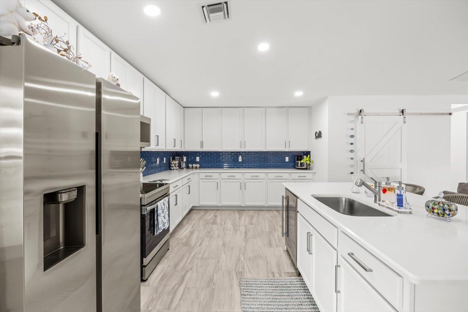 8607 Southwest 7th Lane Okeechobee, FL 34974 - Photo 13 of 44 a large kitchen with stainless steel appliances granite countertop a sink dishwasher a refrigerator and cabinets with wooden floor