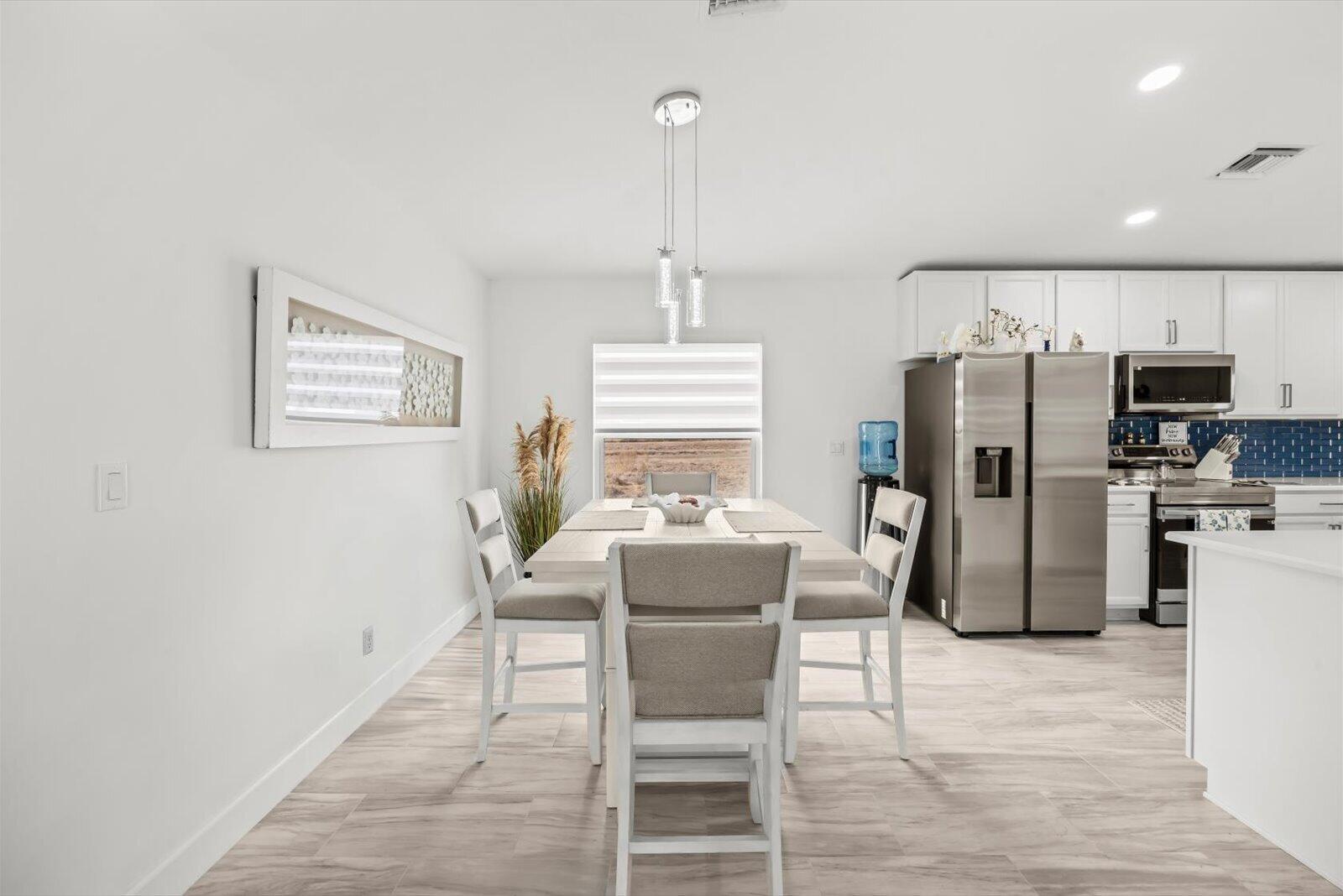 8607 Southwest 7th Lane Okeechobee, FL 34974 - Photo 9 of 44 a dining room with furniture a refrigerator and kitchen view