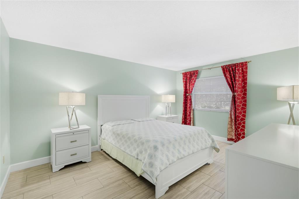 2300 Stickney Point Road, Unit 102 Sarasota, FL 34231 - Photo 12 of 32 a bedroom with a large bed and a wooden floor