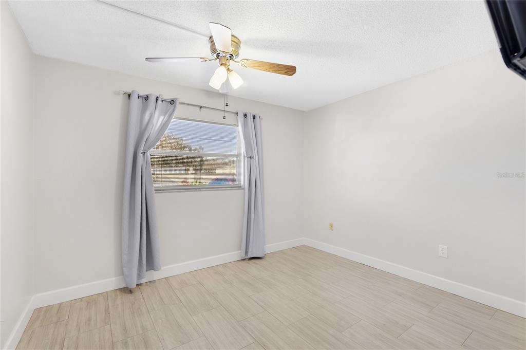 2300 Stickney Point Road, Unit 102 Sarasota, FL 34231 - Photo 17 of 32 an empty room with wooden floor ceiling fan and windows