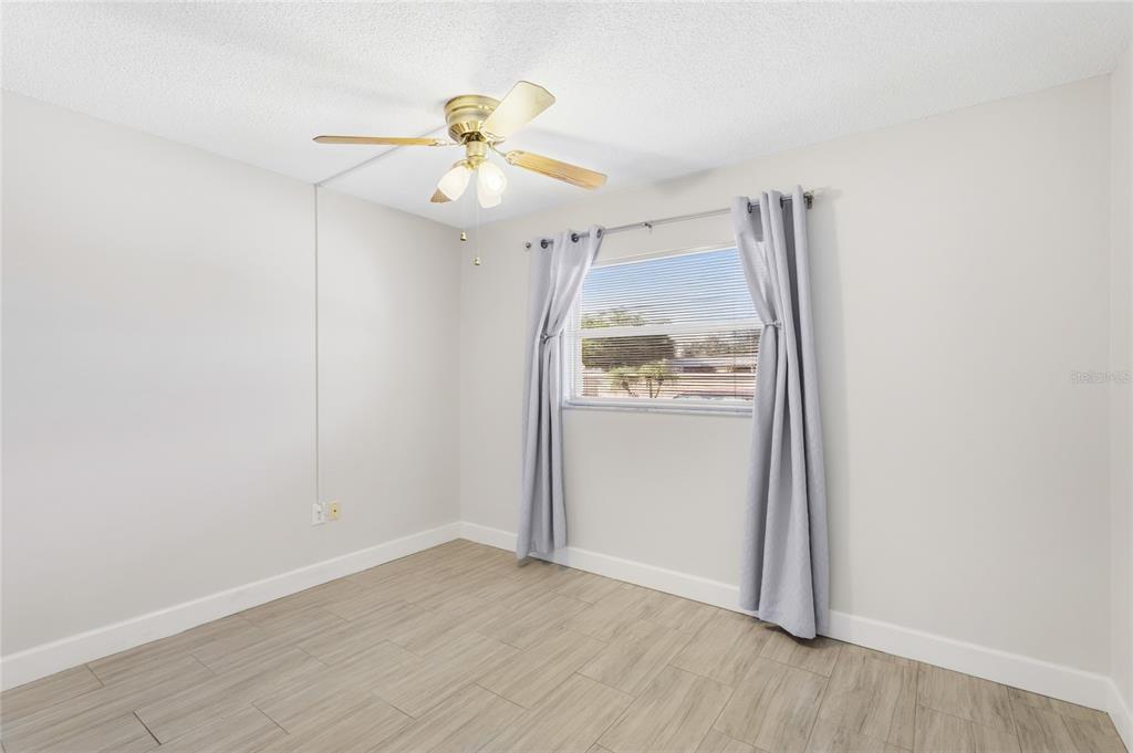 2300 Stickney Point Road, Unit 102 Sarasota, FL 34231 - Photo 18 of 32 an empty room with wooden floor fan and windows