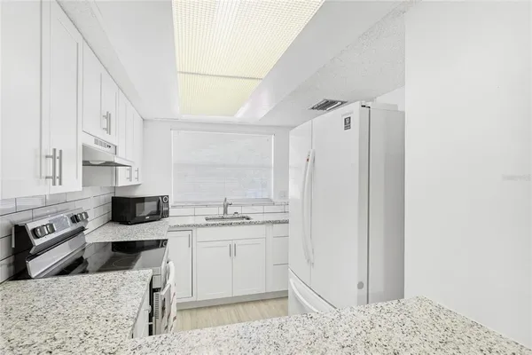 a kitchen with stainless steel appliances kitchen island granite countertop a refrigerator and a sink