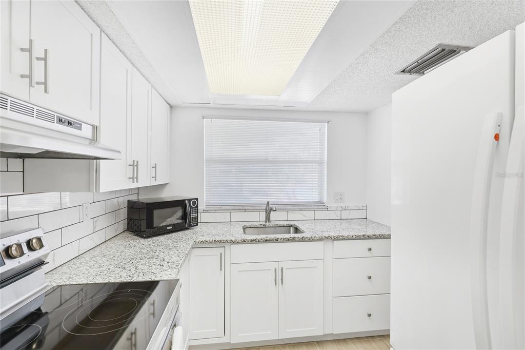 2300 Stickney Point Road, Unit 102 Sarasota, FL 34231 - Photo 9 of 32 a kitchen with granite countertop a sink a stove and cabinets