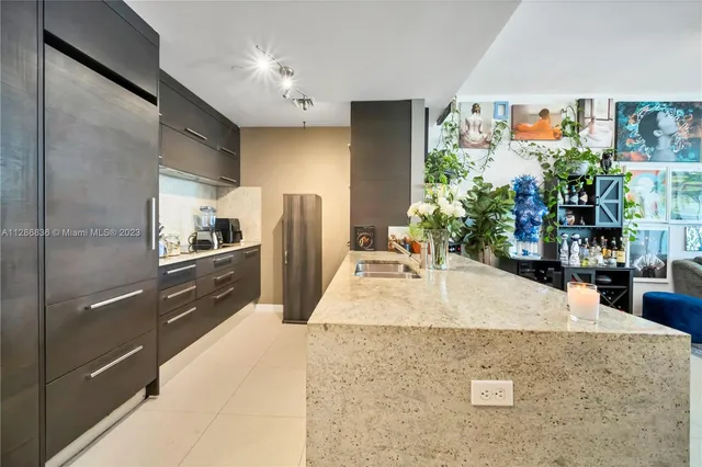 a kitchen with stainless steel appliances kitchen island granite countertop a refrigerator and a counter space