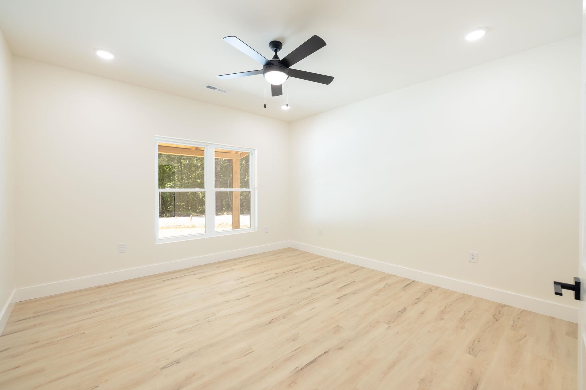 37 William Teague Lane Ramer, TN 38367 - Photo 22 of 39 Neutral tone interior space featuring light wood-finish flooring, a white trim baseboard, and a contrasting black ceiling fan with integrated lighting