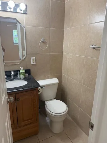 a bathroom with a granite countertop toilet a sink and a mirror