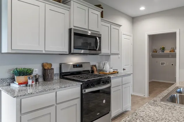 a kitchen with stainless steel appliances granite countertop a stove a sink a microwave a dining table and chairs