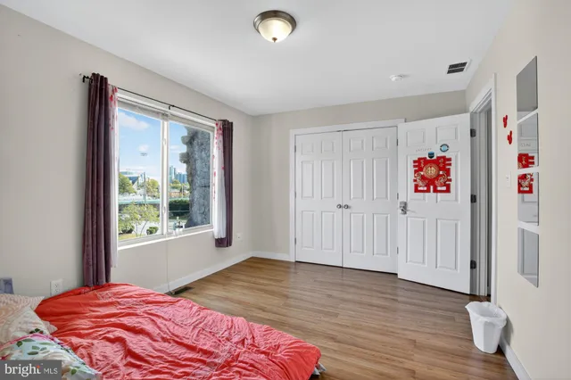 a view of a bedroom with wooden floor and window