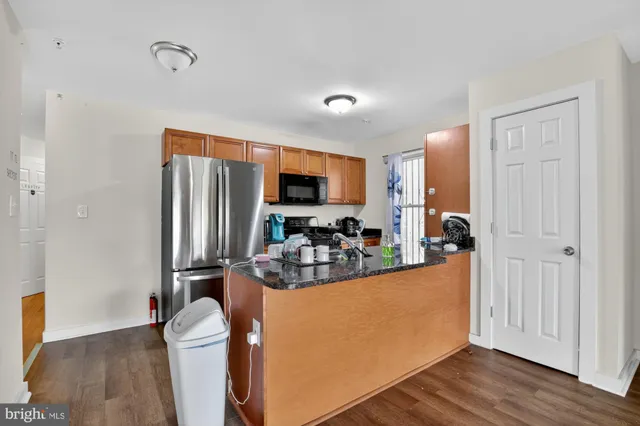 a view of a kitchen with kitchen island stainless steel appliances refrigerator stove and wooden floor