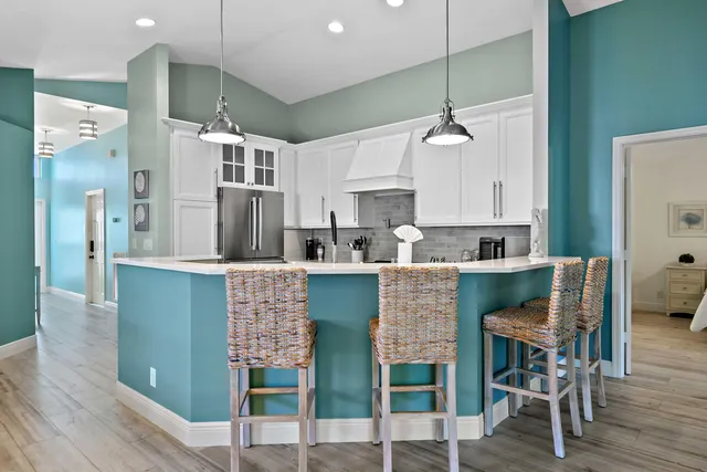 a kitchen with kitchen island granite countertop a refrigerator dining table chairs and sink