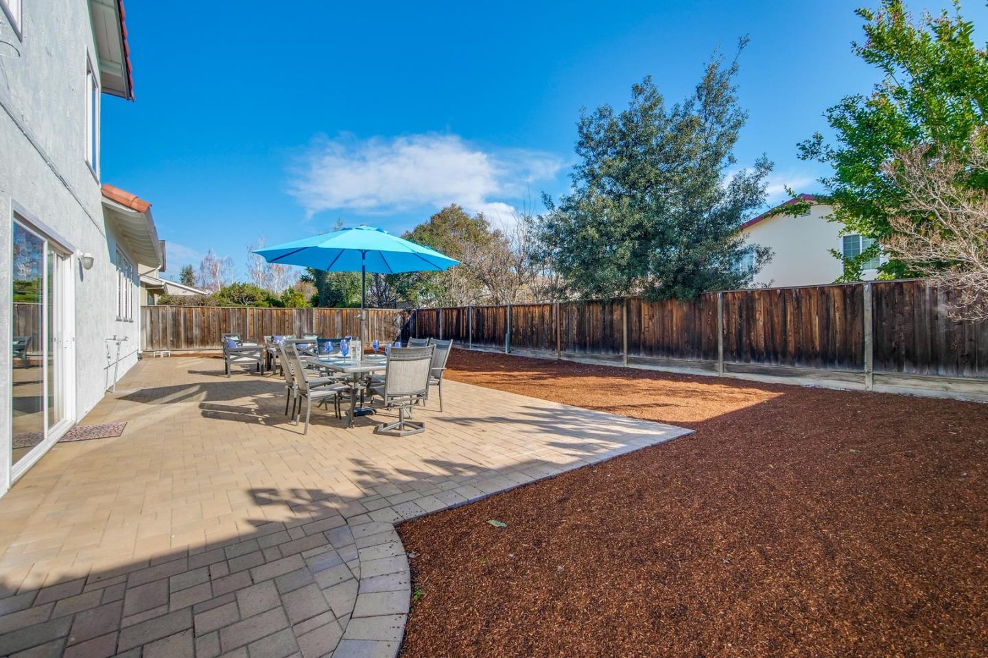 686 Thornapple Drive Sunnyvale, CA 94086 - Photo 70 of 83 a view of a patio with a table and chairs under an umbrella with large trees