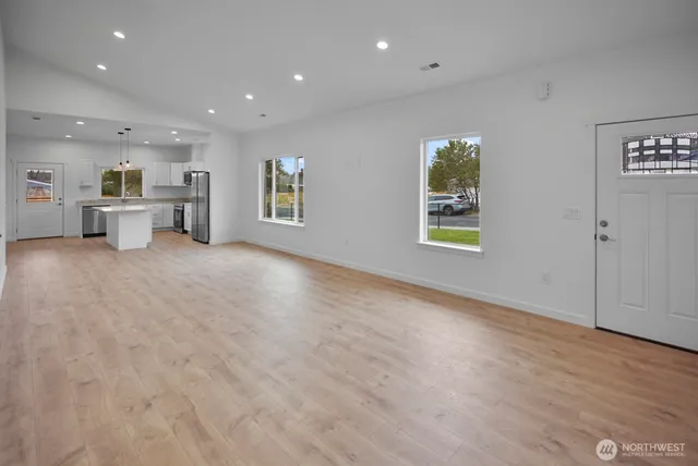 a view of an empty room with window and wooden floor