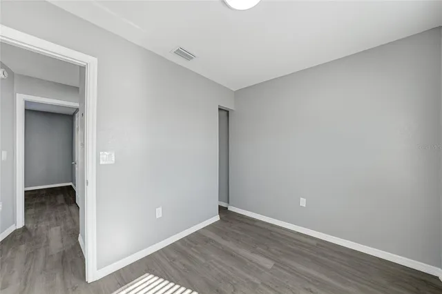 a view of an empty room with wooden floor and closet