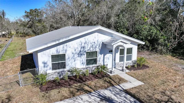 a aerial view of a house with yard and trees in the background