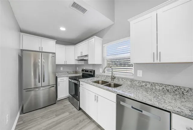 a kitchen with a sink white cabinets and stainless steel appliances