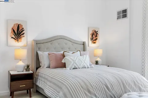 a bedroom with a bed and a lamp on dresser