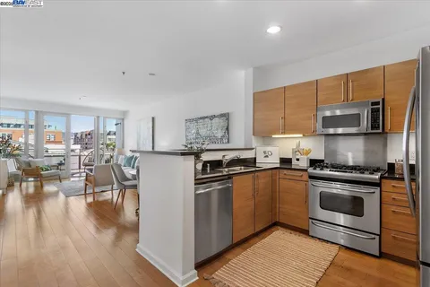 a kitchen with stainless steel appliances granite countertop a stove top oven a sink dishwasher a refrigerator and white cabinets with wooden floor