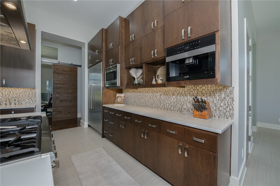 3320 Sycamore Trail Bryan, TX 77807 - Photo 12 of 48 Kitchen with light countertops, tasteful backsplash, built in appliances, dark brown cabinets, and ventilation hood