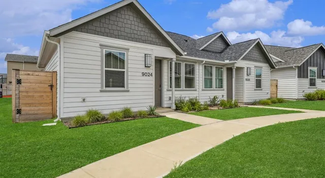 a view of a house with a small yard and a large tree