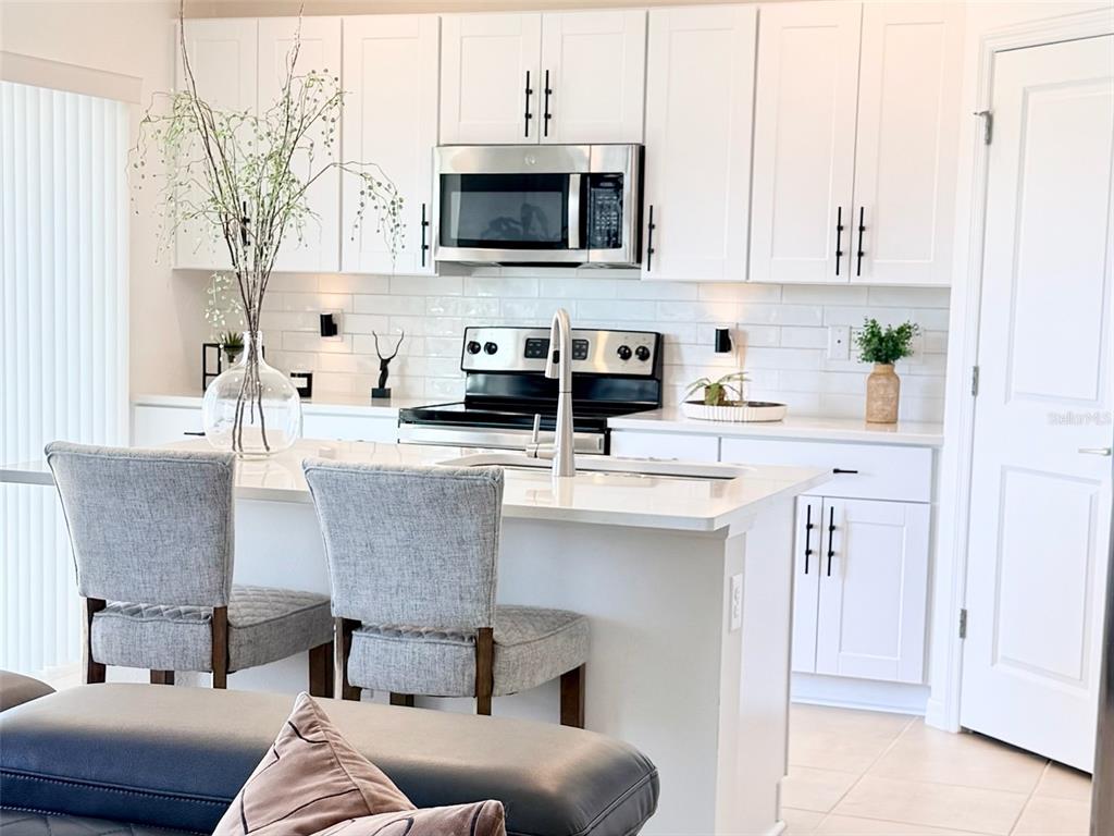 1126 Calico Pointe Circle Groveland, FL 34736 - Photo 9 of 28 a kitchen with kitchen island granite countertop a stove a sink a microwave a refrigerator and white cabinets with wooden floor