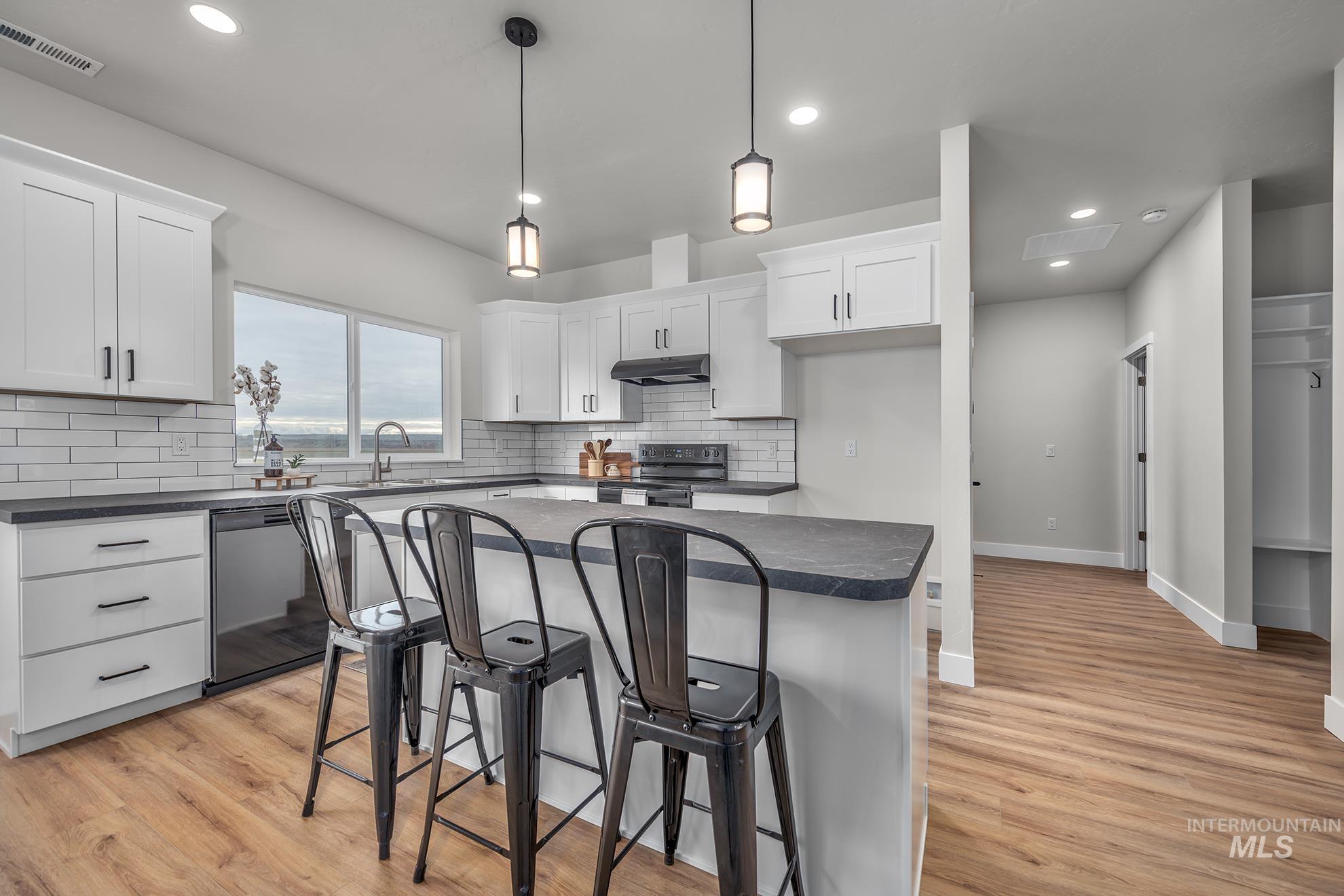 1367 Hansen Road Weiser, ID 83672 - Photo 8 of 36 Kitchen with a breakfast bar, pendant lighting, a kitchen island, electric range, and light wood-style flooring