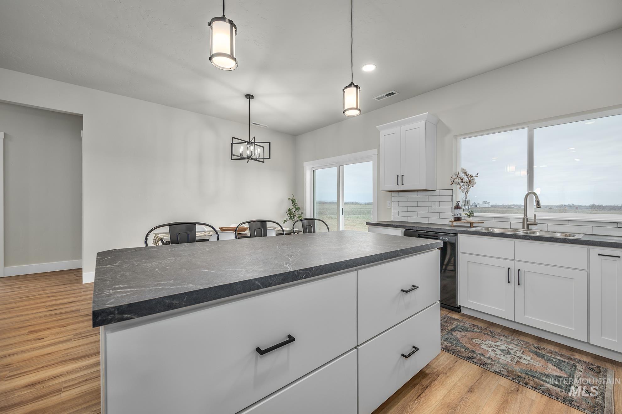 1367 Hansen Road Weiser, ID 83672 - Photo 9 of 36 Kitchen featuring decorative backsplash, light wood-style flooring, white cabinets, black dishwasher, and hanging lights