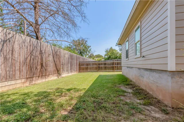 a view of backyard with wooden fence