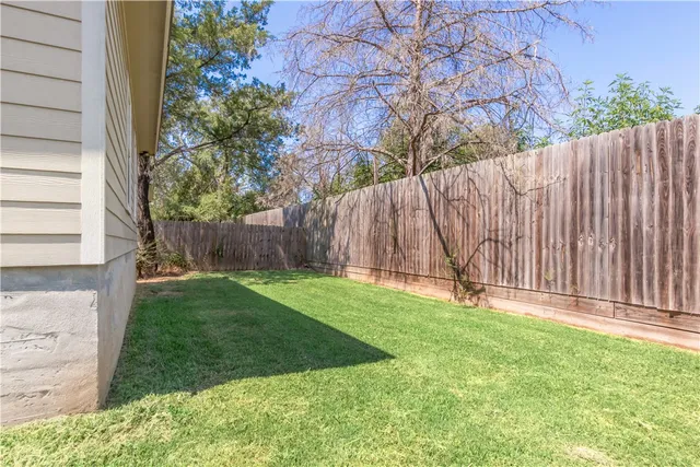 a backyard of a house with lots of green space and wooden fence