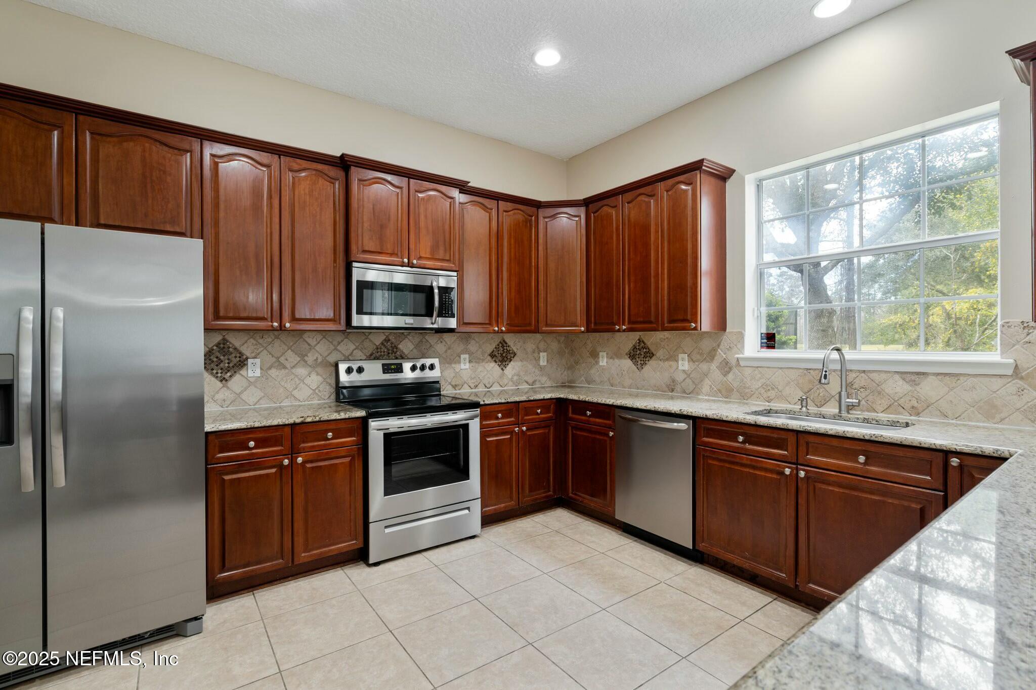 2448 Country Side Drive Fleming Island, FL 32003 - Photo 16 of 46 a kitchen with stainless steel appliances granite countertop wooden cabinets a sink and a stove