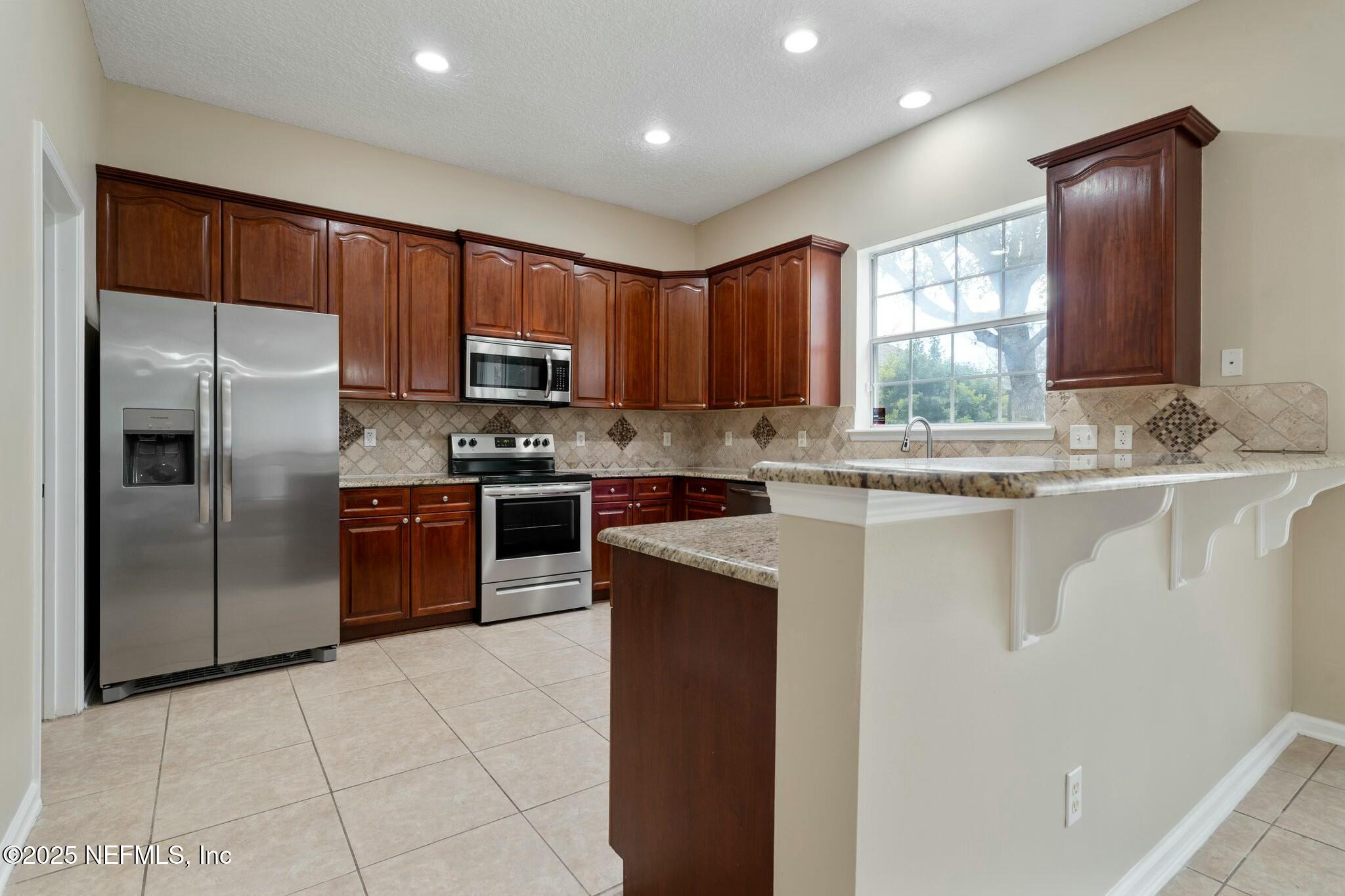 2448 Country Side Drive Fleming Island, FL 32003 - Photo 17 of 46 a kitchen with stainless steel appliances granite countertop a refrigerator sink and cabinets