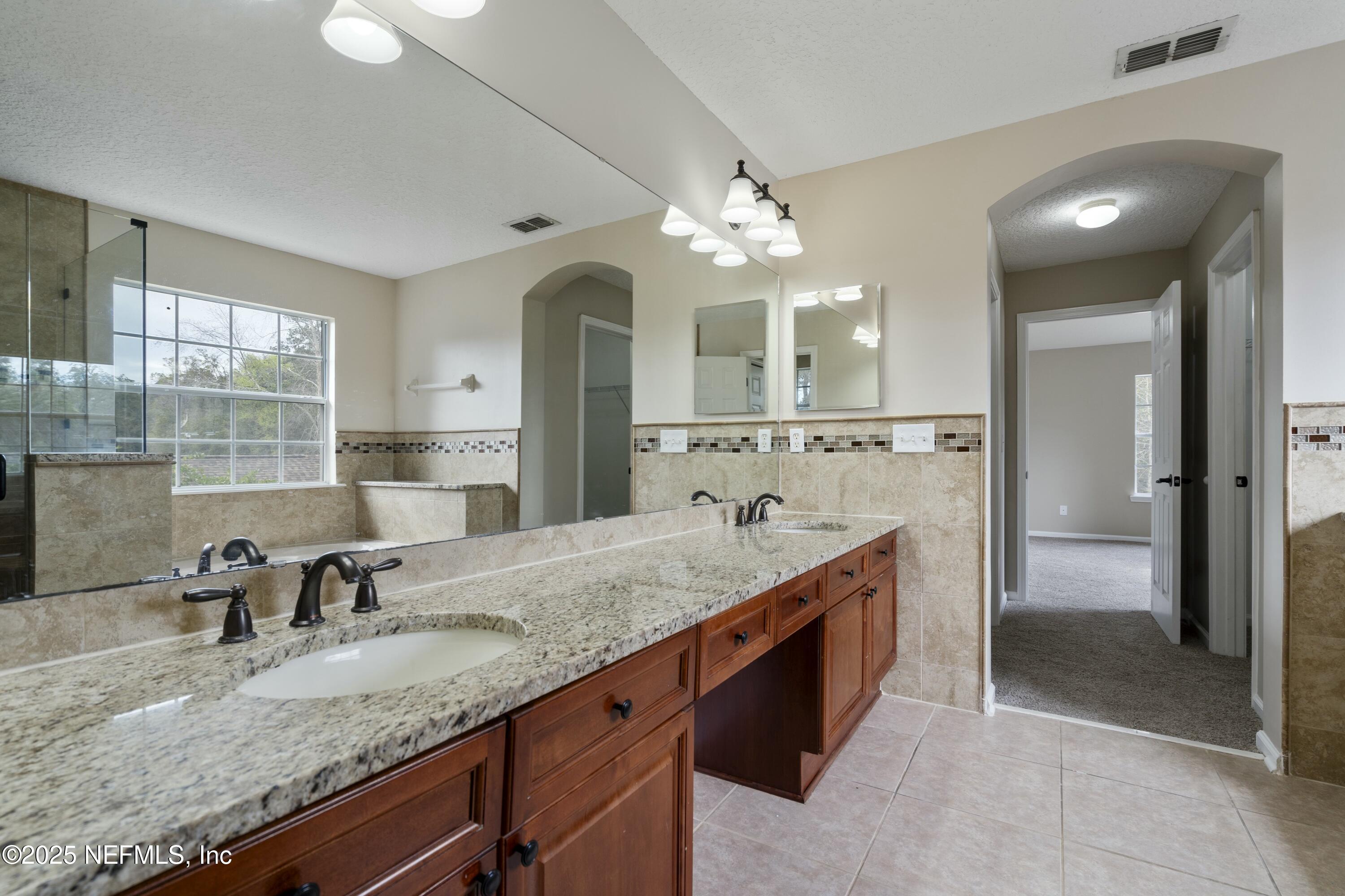 2448 Country Side Drive Fleming Island, FL 32003 - Photo 22 of 46 a spacious bathroom with a granite countertop sink a mirror and shower