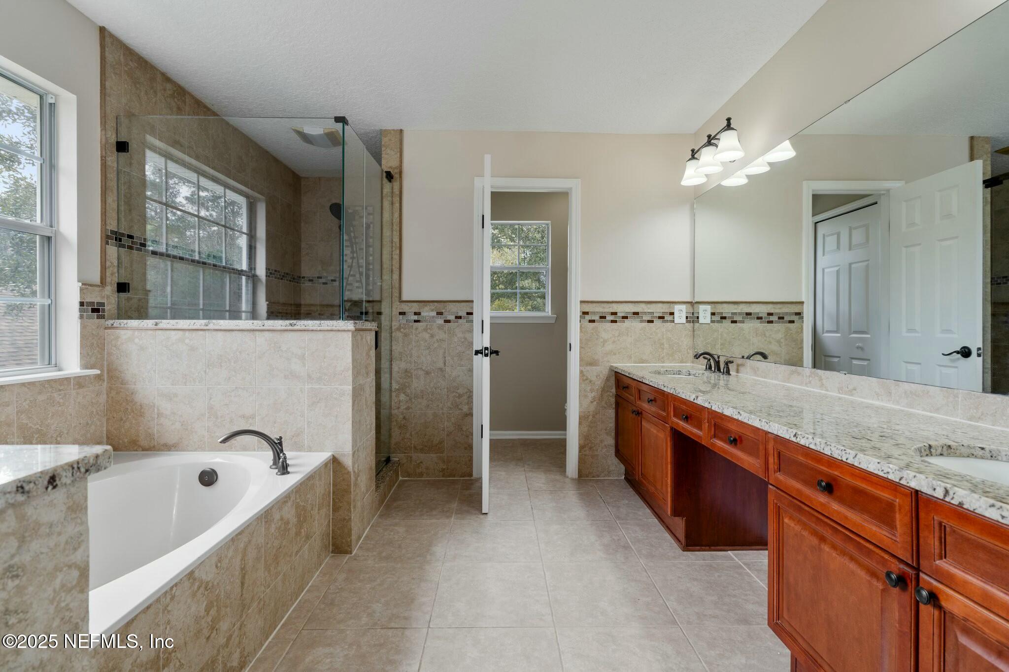 2448 Country Side Drive Fleming Island, FL 32003 - Photo 3 of 46 a large spacious bathroom with a granite countertop tub sink and mirror