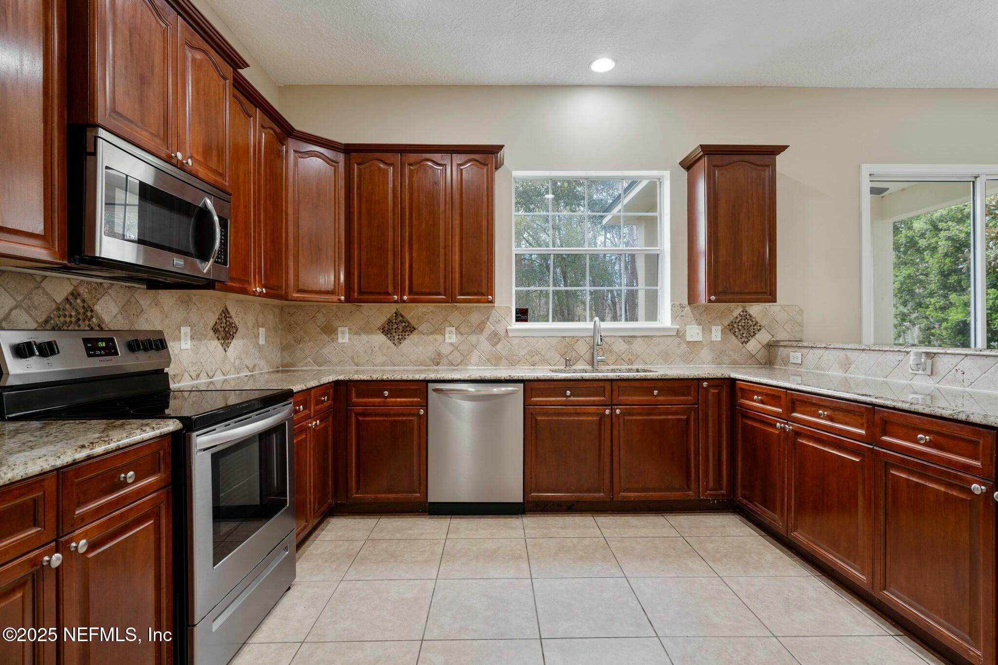 2448 Country Side Drive Fleming Island, FL 32003 - Photo 4 of 46 a kitchen with stainless steel appliances granite countertop a stove microwave and sink