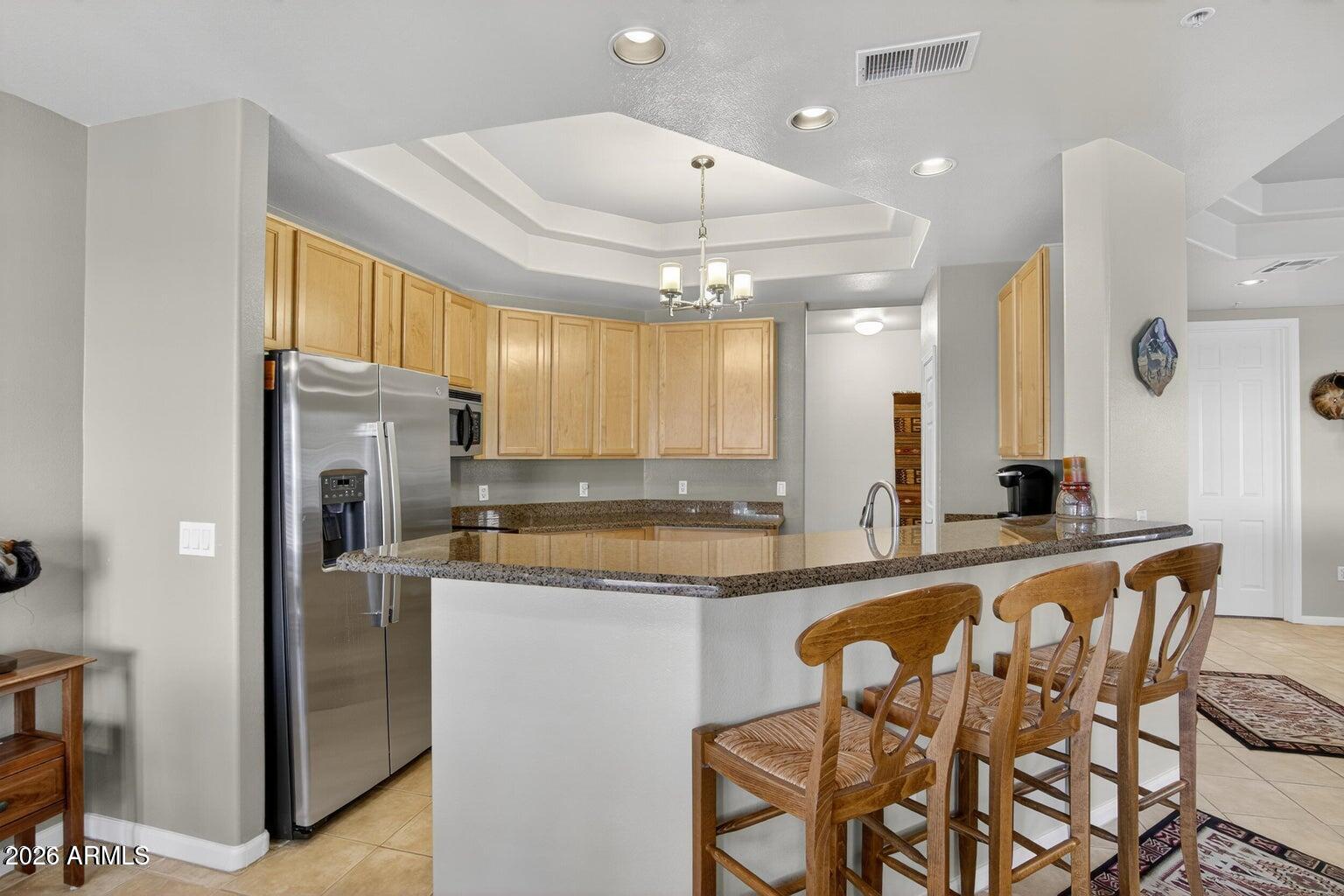 8245 East Bell Road, Unit 121 Scottsdale, AZ 85260 - Photo 6 of 22 a kitchen with granite countertop a table chairs stove a refrigerator and cabinets