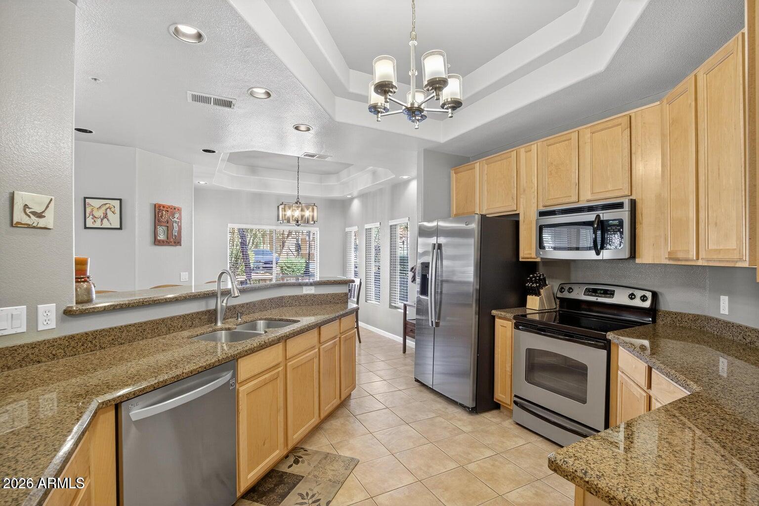 8245 East Bell Road, Unit 121 Scottsdale, AZ 85260 - Photo 7 of 22 a kitchen with stainless steel appliances granite countertop a stove sink and refrigerator