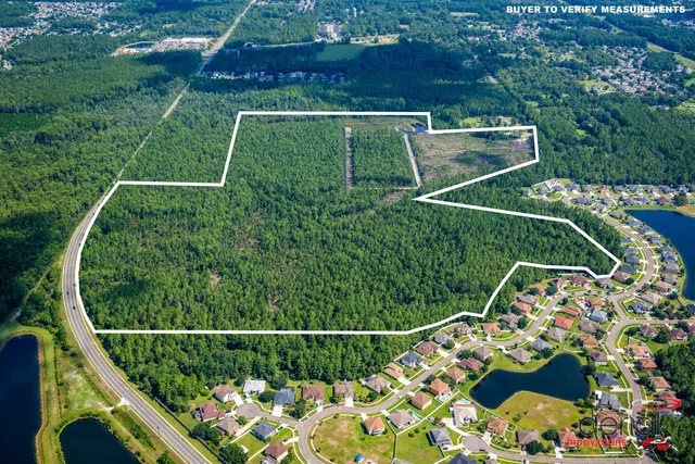 an aerial view of a residential houses with outdoor space and trees