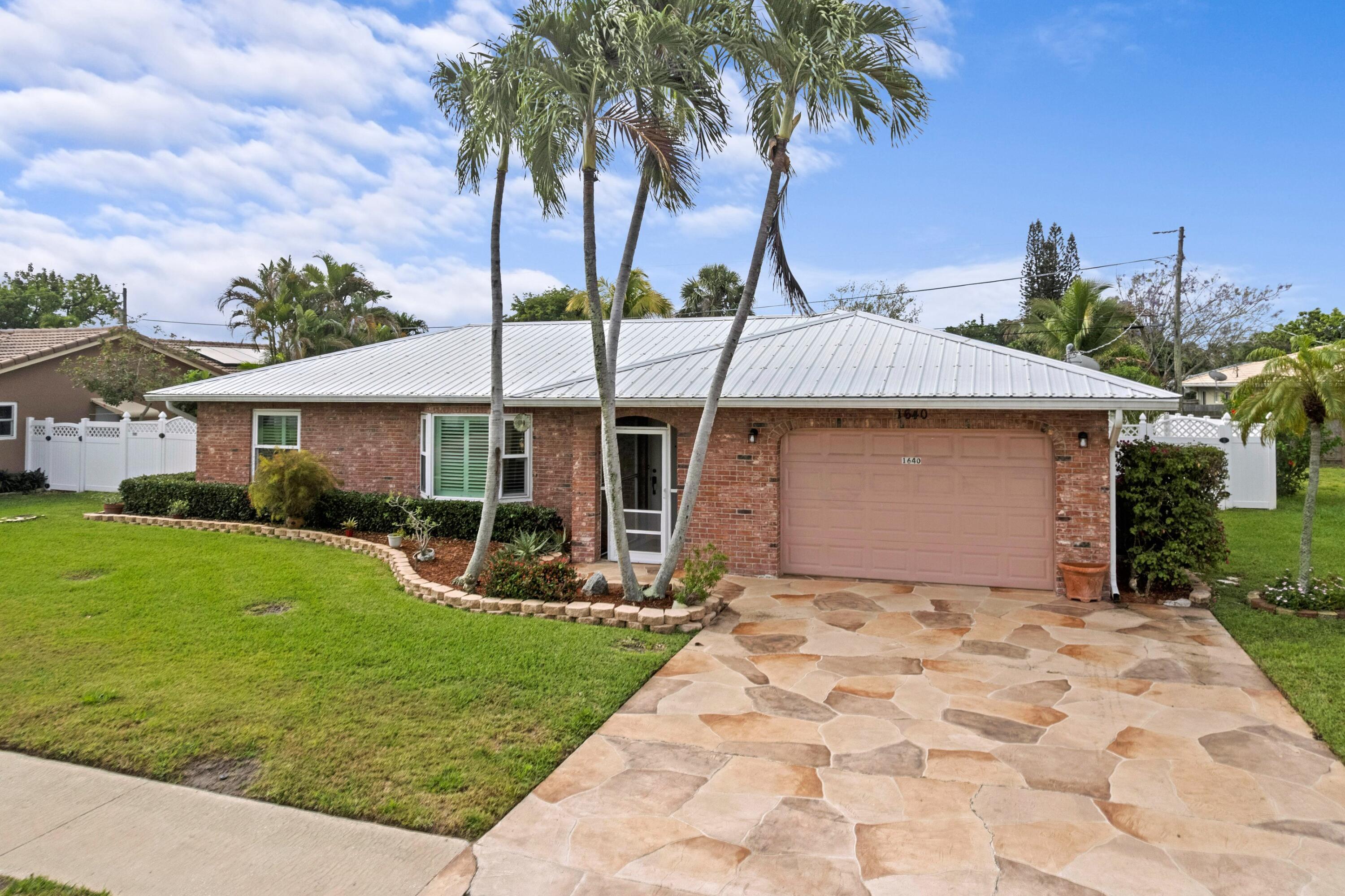 1640 Northwest 10th Street Boca Raton, FL 33486 - Photo 25 of 40 a front view of a house with a garden and tree