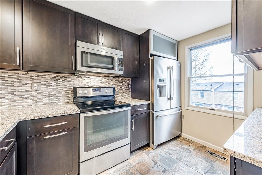 314 Quail Run Road Venetia, PA 15367 - Photo 9 of 24 a kitchen with granite countertop wooden cabinets stainless steel appliances and a window