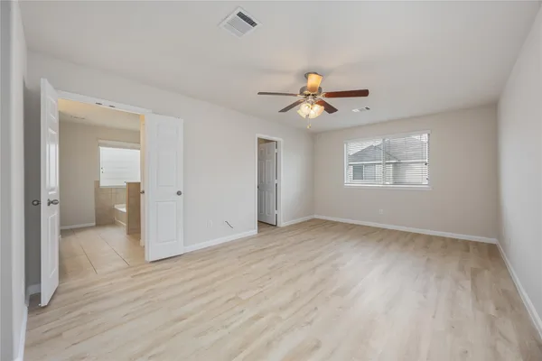 a view of an empty room with a ceiling fan and wooden floor