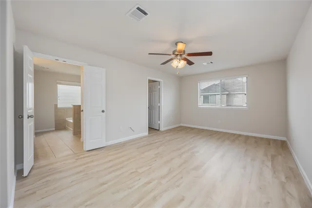 a view of an empty room with a ceiling fan and wooden floor