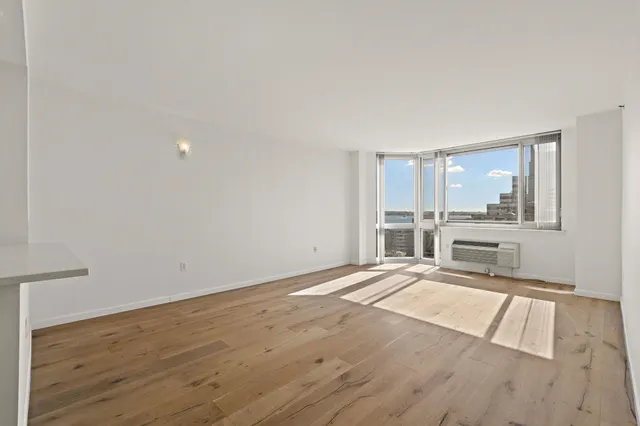 a view of an empty room with wooden floor and a window