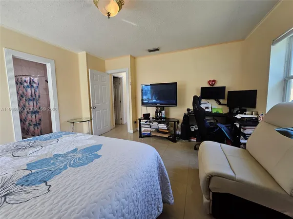 a bedroom with bed a computer on the desk and a dresser