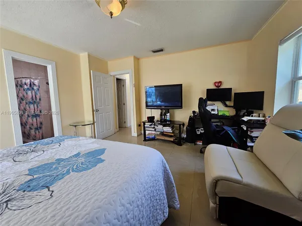 a bedroom with bed a computer on the desk and a couch